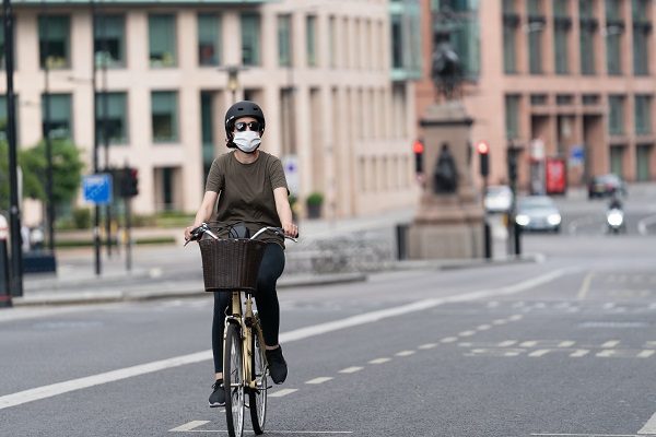 Mulher pedalando em Londres de máscara